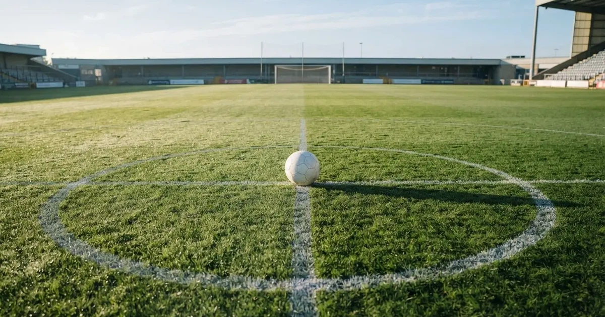 Un balón en el punto central de un campo de césped a la luz de la mañana