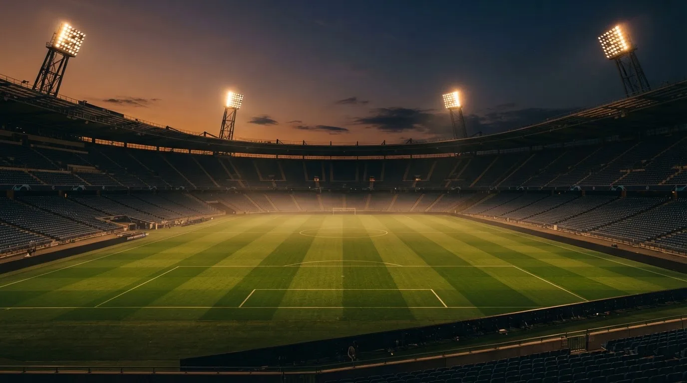 Un estadio de fútbol vacío con torres de iluminación al atardecer