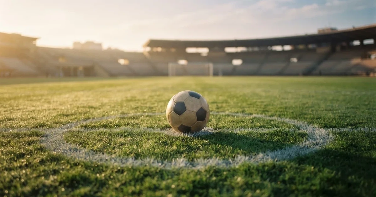Un balón en el punto central de un campo de césped a la luz de la mañana