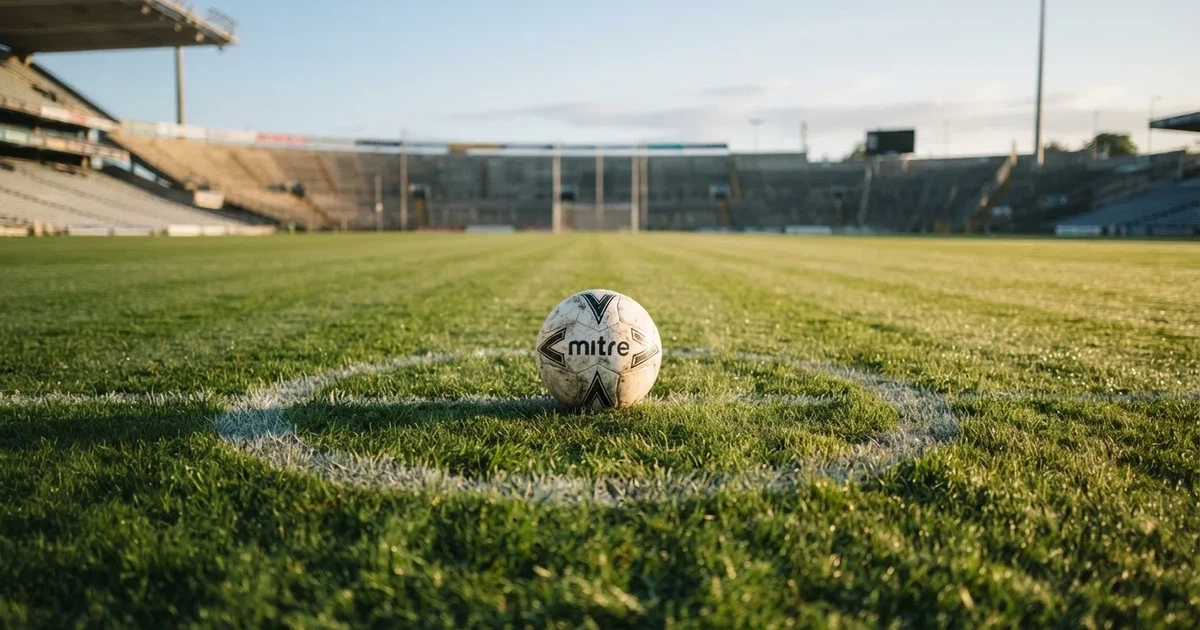 Un balón en el punto central de un campo de césped a la luz de la mañana