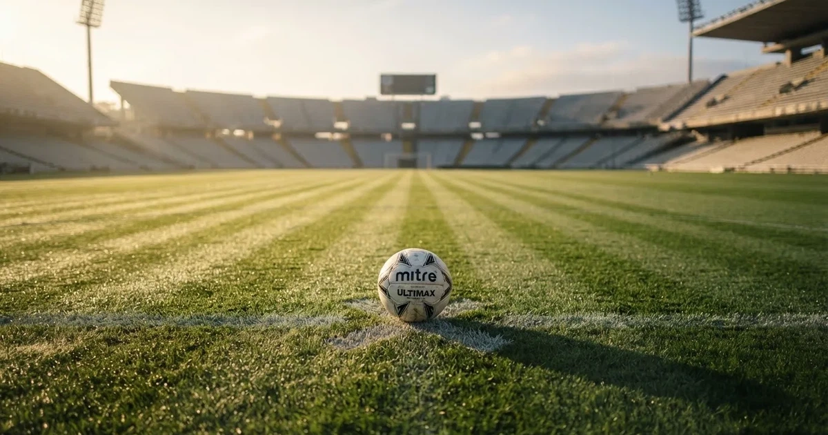 Un balón en el punto central de un campo de césped a la luz de la mañana
